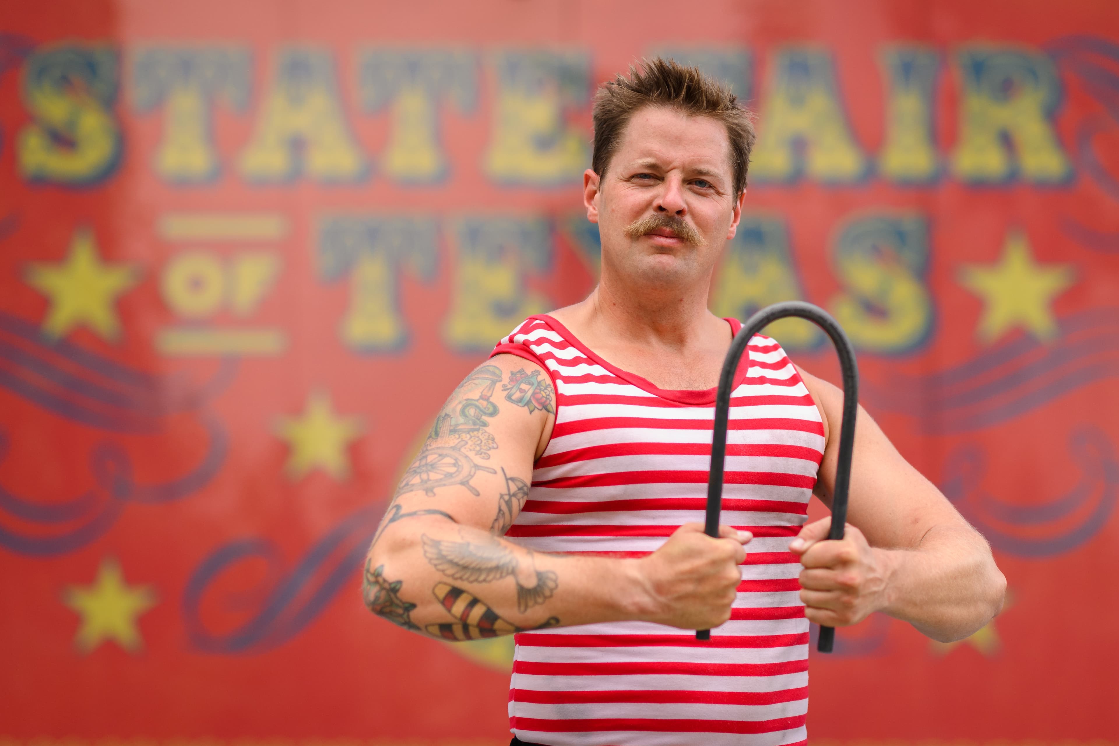 File photo: A performer in a striped outfit holds a bent metal bar onstage.